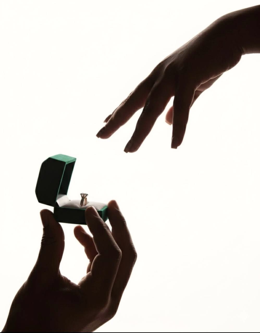 Deux mains, l'une tend l'écrin avec la bague, l'autre s'avance